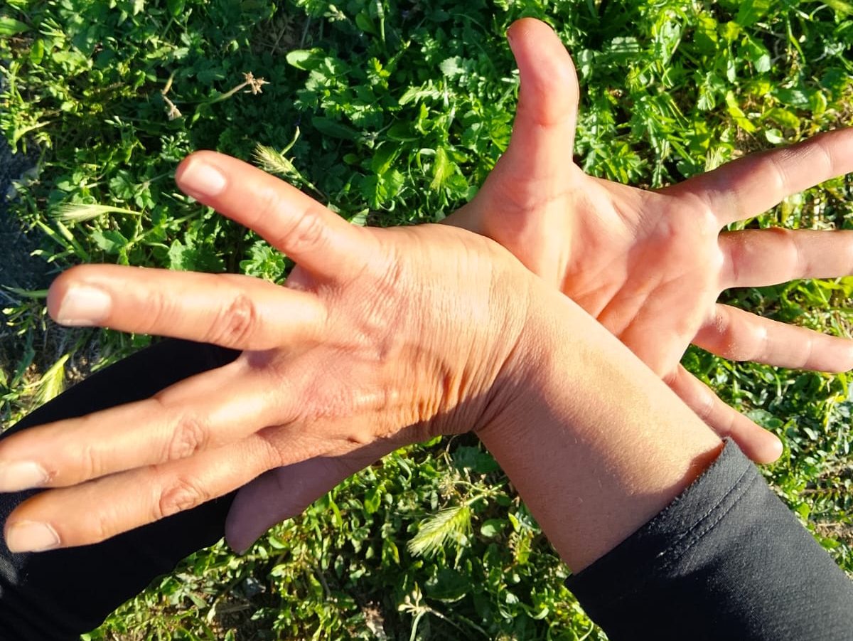 Le mani intrecciate nell'erba, gesto simbolico di equilibrio e connessione con la Natura